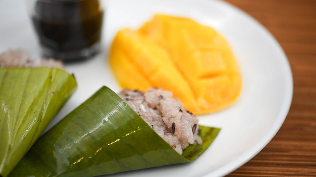 Close-up of mango sticky rice served on a banana leaf with coconut cream drizzled on top