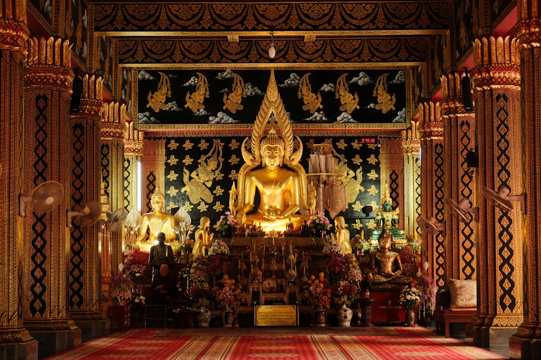 Golden Buddha statue inside the teak viharn at Wat Lok Moli, with intricate Lanna woodcarving on the ceiling