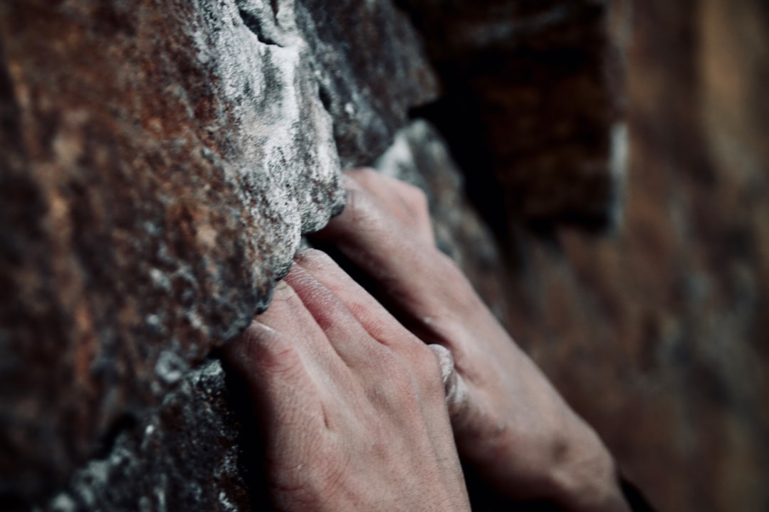 Close-up of hands gripping limestone holds on a tufa-covered cliff face in Krabi