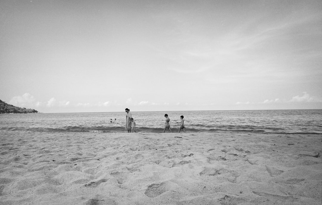 Aerial view of Kata Beach with turquoise water, white sand, and green hills in the background
