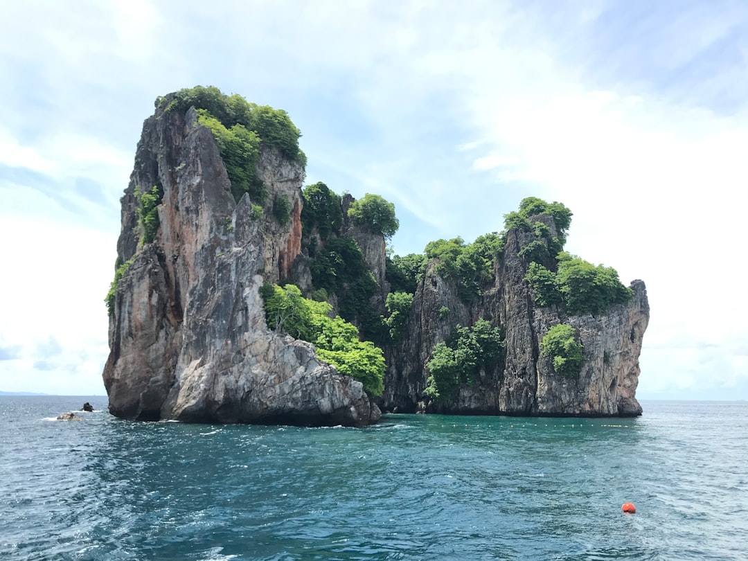 Longtail boat floating on crystal clear water near limestone cliffs in Phang Nga Bay